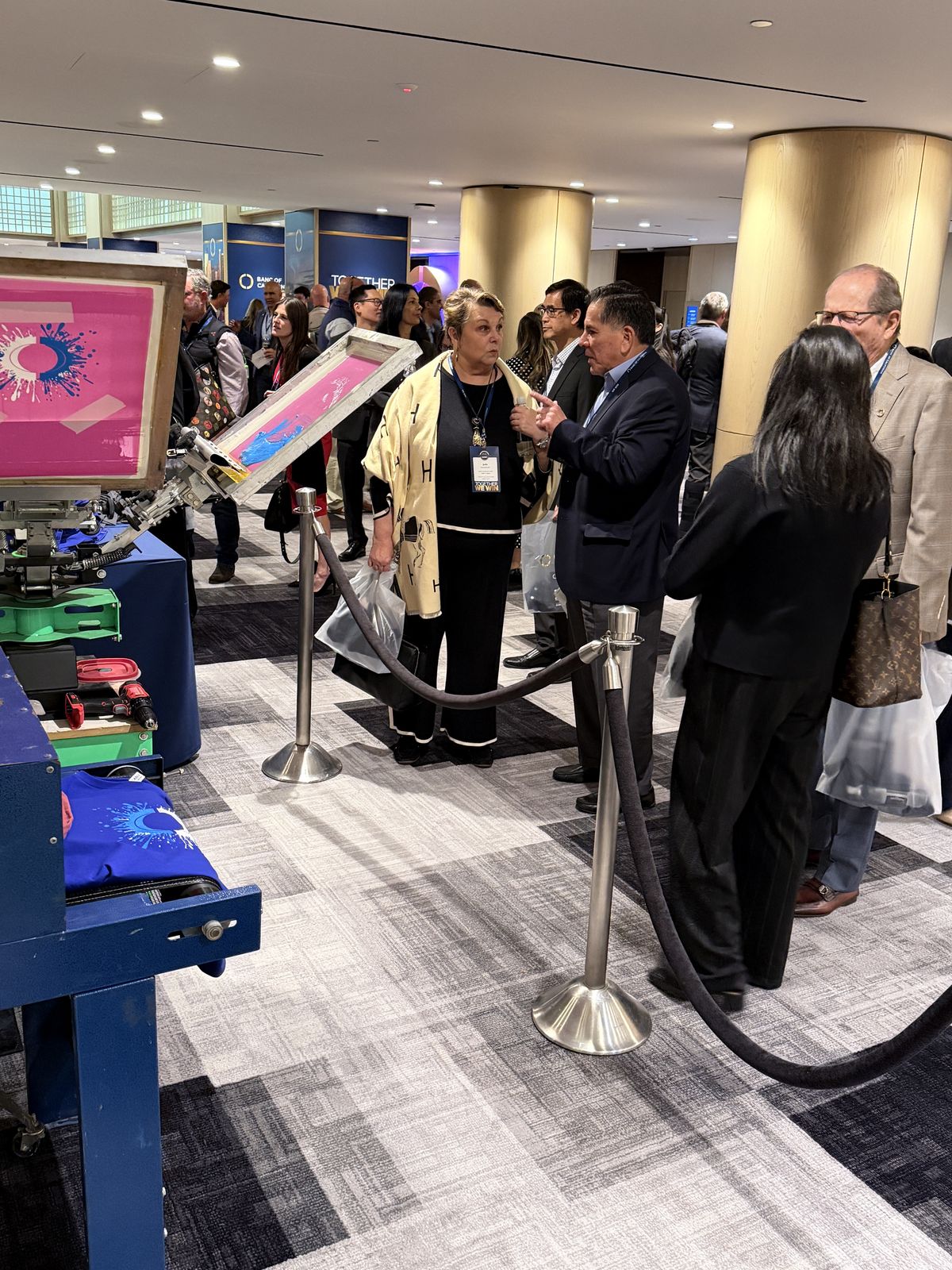 Guests waiting behind stanchion ropes at a live customization station inside a hotel event space