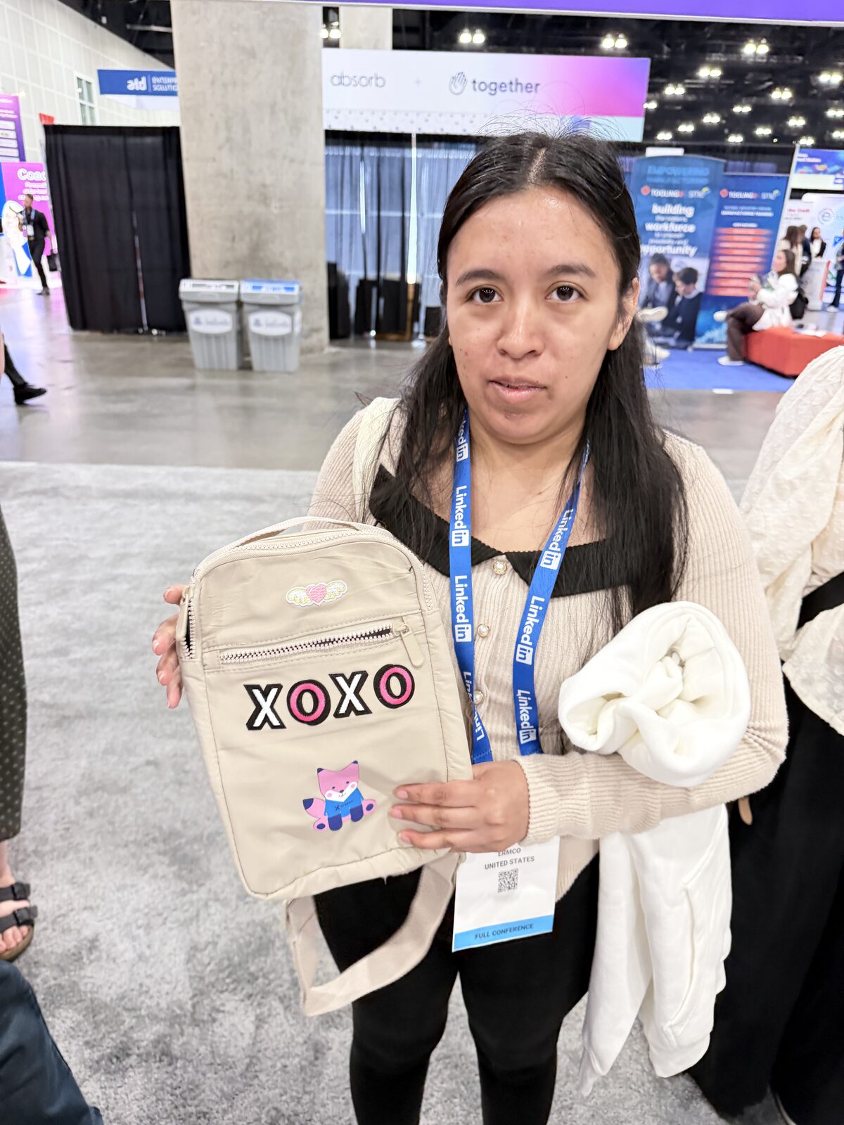 Smiling guest holding up a cream crossbody bag customized with chenille letter patches at a convention