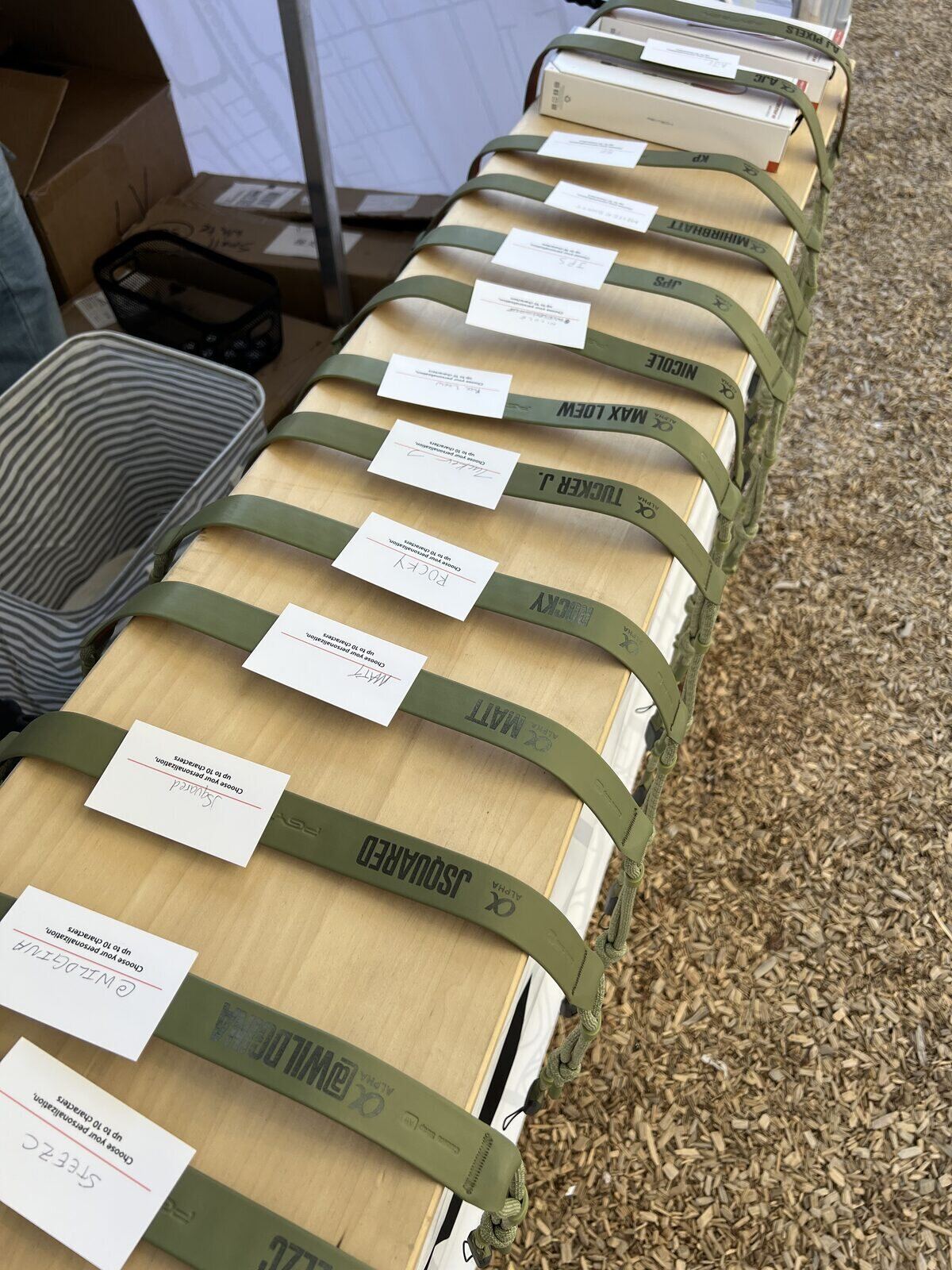 Rows of labeled personalization orders staged on a table at an outdoor event booth