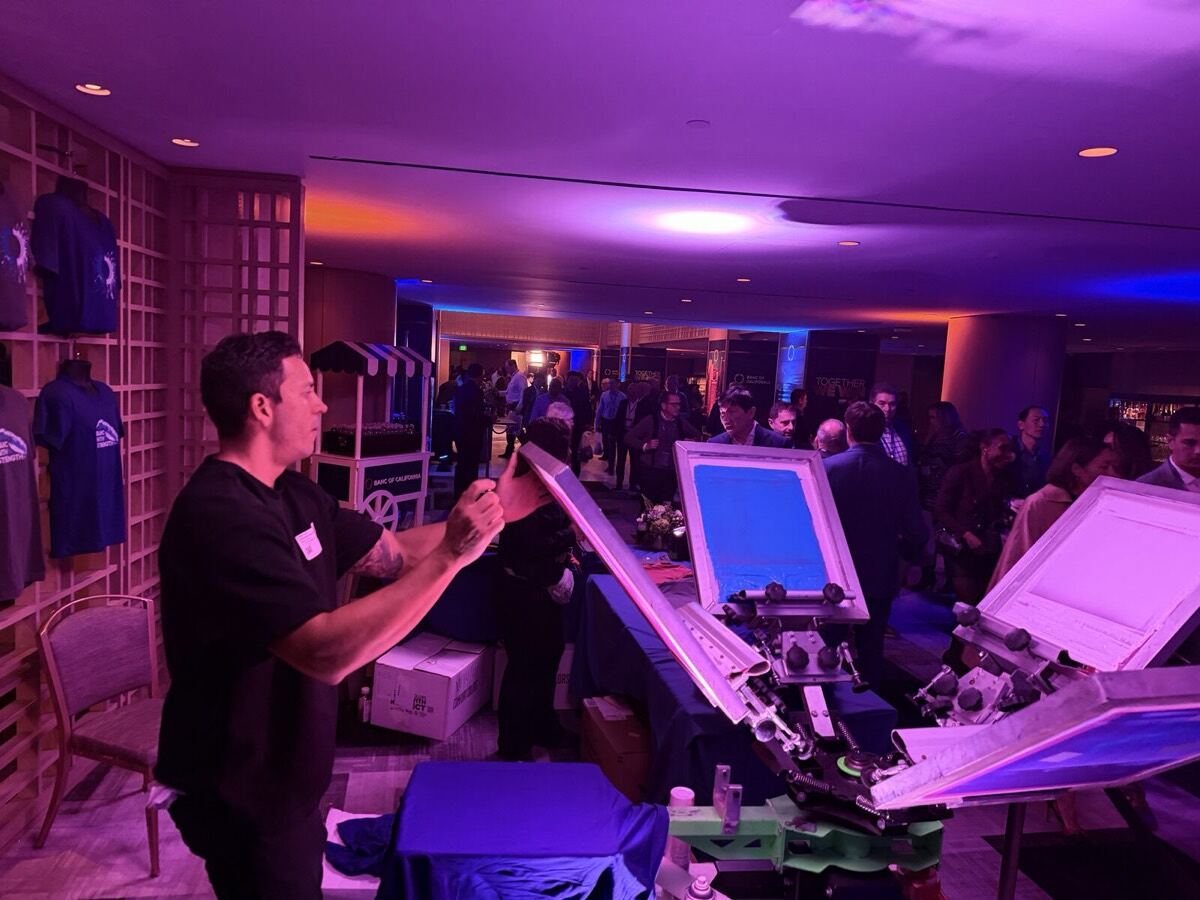 Crew member running the live customization station as an evening reception fills the room